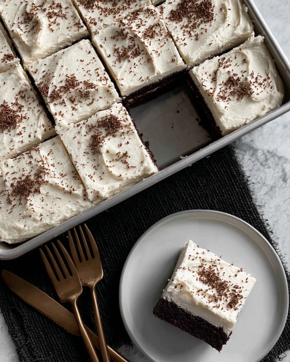 The image shows a chocolate cake cut into nine square pieces in a silver baking pan with one piece missing, revealing a dark, moist chocolate layer underneath a thick, creamy white frosting spread smoothly with visible ridges. The frosting is sprinkled lightly with fine chocolate shavings and has a soft, airy texture. On a white plate below the pan, a single cake slice mirrors the layered look with a dark brown chocolate base and a thick white frosting top, also sprinkled with chocolate bits. Beside the plate are two bronze-colored forks on a black textured surface, all sitting on a white marbled background. Photo taken with an iphone --ar 4:5 --v 7