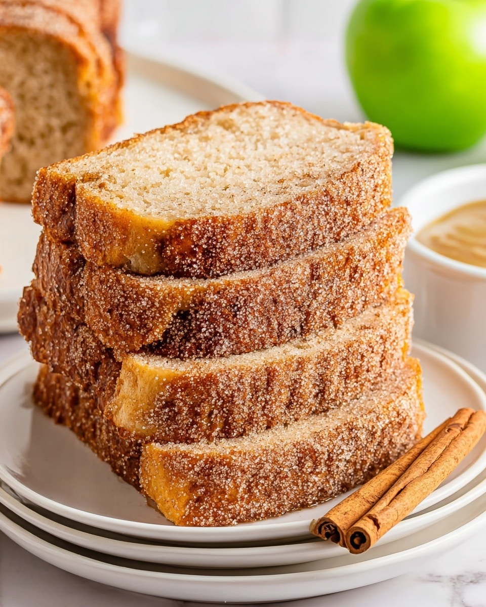 The image shows a stack of three thick slices of cinnamon sugar-covered bread on a white plate. Each slice has a golden-brown crust coated with a grainy layer of cinnamon sugar, while the inside has a soft, light beige texture with a slightly crumbly look. Two cinnamon sticks rest beside the bread on the plate. In the background, there is a green apple and a white bowl with light-colored spread or dip, all placed on a white marbled surface. Photo taken with an iphone --ar 4:5 --v 7