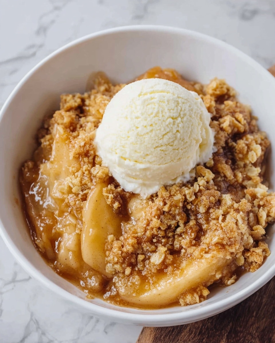 A white bowl filled with a warm apple crumble dessert, showing three main layers: at the bottom, soft cooked apple slices in a light caramel sauce with a shiny texture; on top of the apples, a golden crumbly oat topping that looks crunchy and unevenly spread; sitting in the center on top of the crumble is a single round scoop of smooth white vanilla ice cream. The background has a white marbled texture. photo taken with an iphone --ar 4:5 --v 7