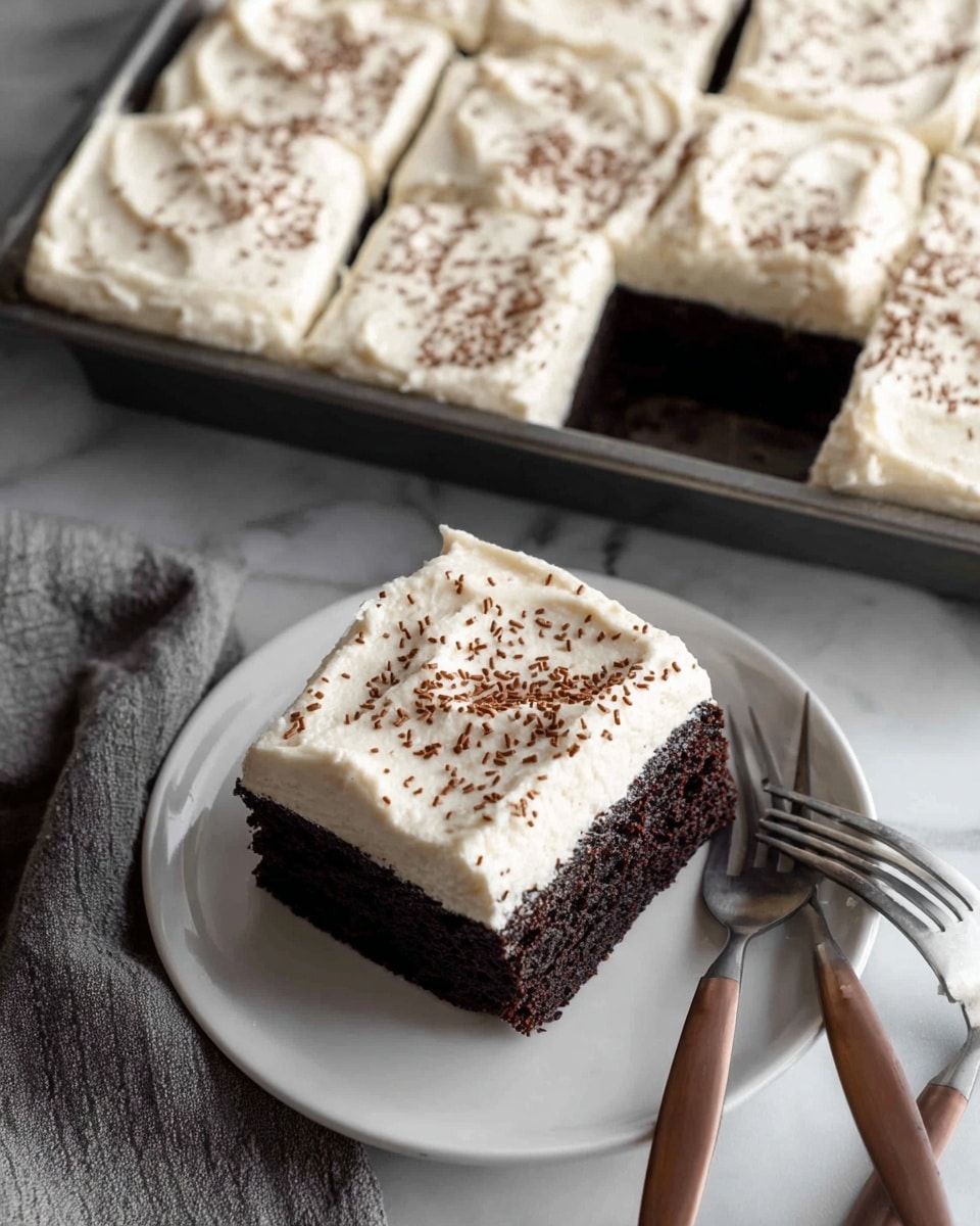 A square piece of dark chocolate cake with two layers sits on a white plate. The cake has a thick, creamy white frosting on top, spread evenly with soft, swirled texture, and tiny chocolate sprinkles scattered all over the surface. The cake itself is dense and moist with a rich dark brown color. It is cut from a larger tray filled with nine similar square pieces, where one piece is already taken out, showing the dark cake layer beneath the white frosting. Next to the plate are three brown forks stacked on a white marbled surface. photo taken with an iphone --ar 4:5 --v 7