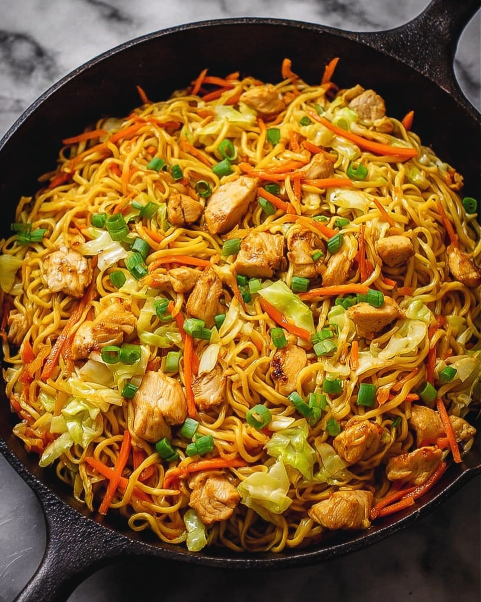 The image shows a black cast iron pan filled with a colorful stir-fried noodle dish. The dish has one main layer of yellow noodles mixed evenly with bright orange thin carrot strips, light green pieces of cabbage, and scattered small green onion slices. On top, there are medium-sized chunks of cooked chicken with a golden brown color spread throughout. The background is a white marbled texture. photo taken with an iphone --ar 4:5 --v 7