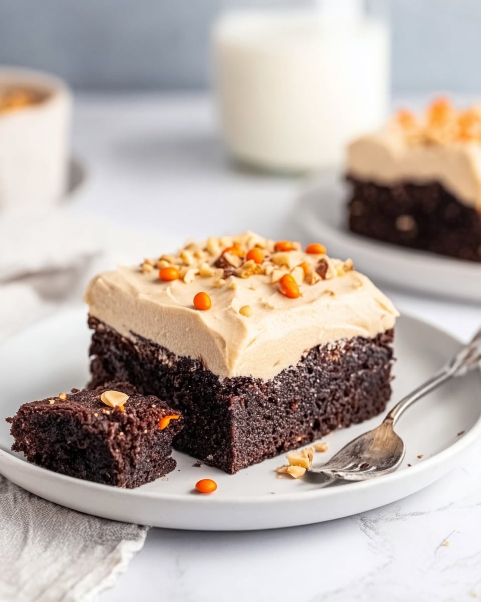 The image shows a two-layer dessert square on a white plate placed on a white marbled surface. The bottom layer is thick, dark brown, and moist chocolate cake. The top layer is a thick, light beige frosting, smooth in texture, decorated with small pieces of nuts and orange candy bits scattered on top. A small piece of the cake square is cut and pulled slightly away from the main piece with a spoon nearby, behind it. A glass of milk is blurred in the background. Photo taken with an iphone --ar 4:5 --v 7