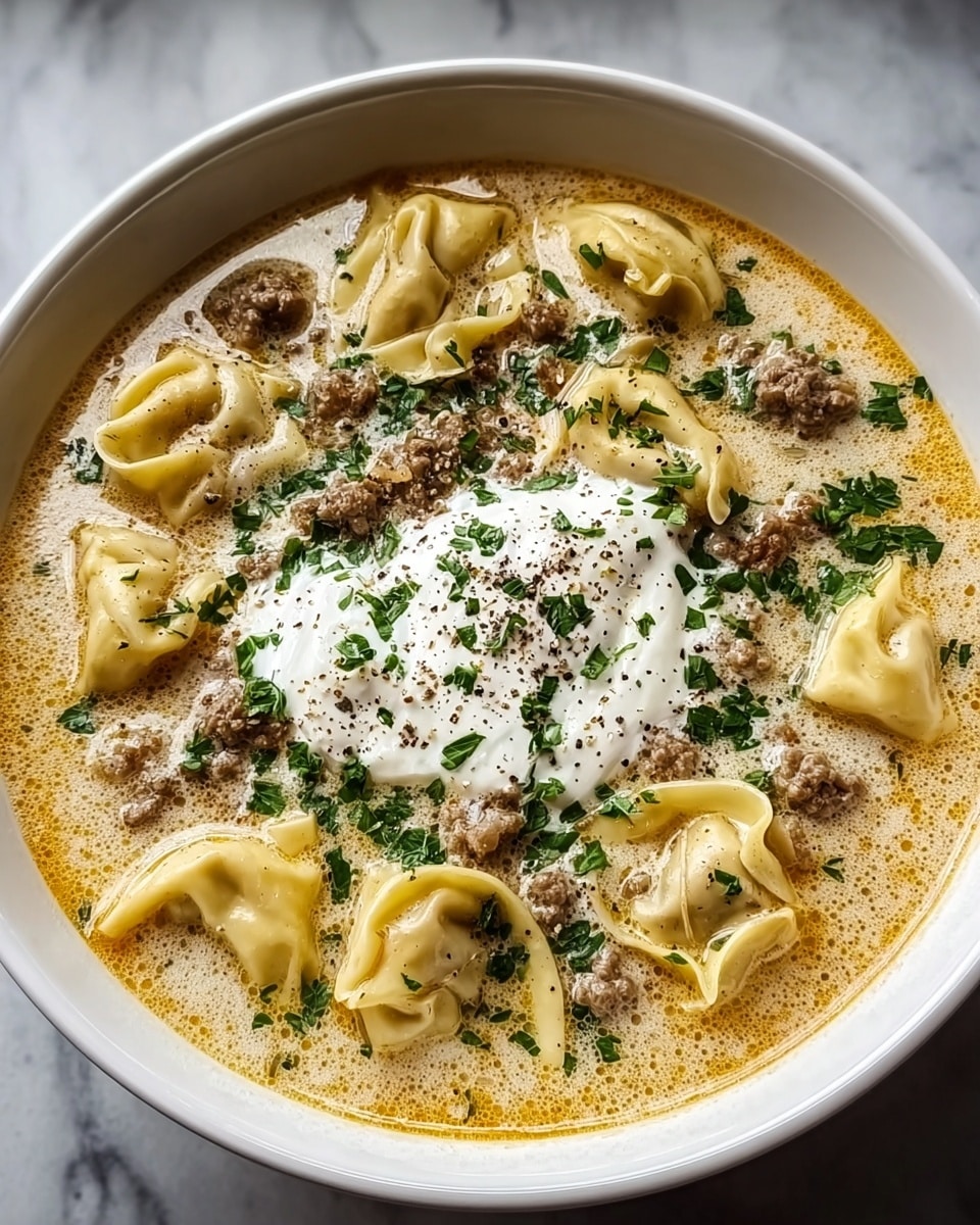 A white bowl filled with creamy soup with a light yellow color base, floating with large pasta shapes that look soft and curled around the edges. There are browned ground meat pieces scattered throughout the soup, with fresh green chopped herbs sprinkled on top. In the center, two dollops of white sour cream sit, lightly dusted with black pepper. The bowl is placed on a white marbled surface that adds a clean and bright feel to the image. The soup looks warm and rich with a slightly oily sheen in parts. Photo taken with an iphone --ar 4:5 --v 7