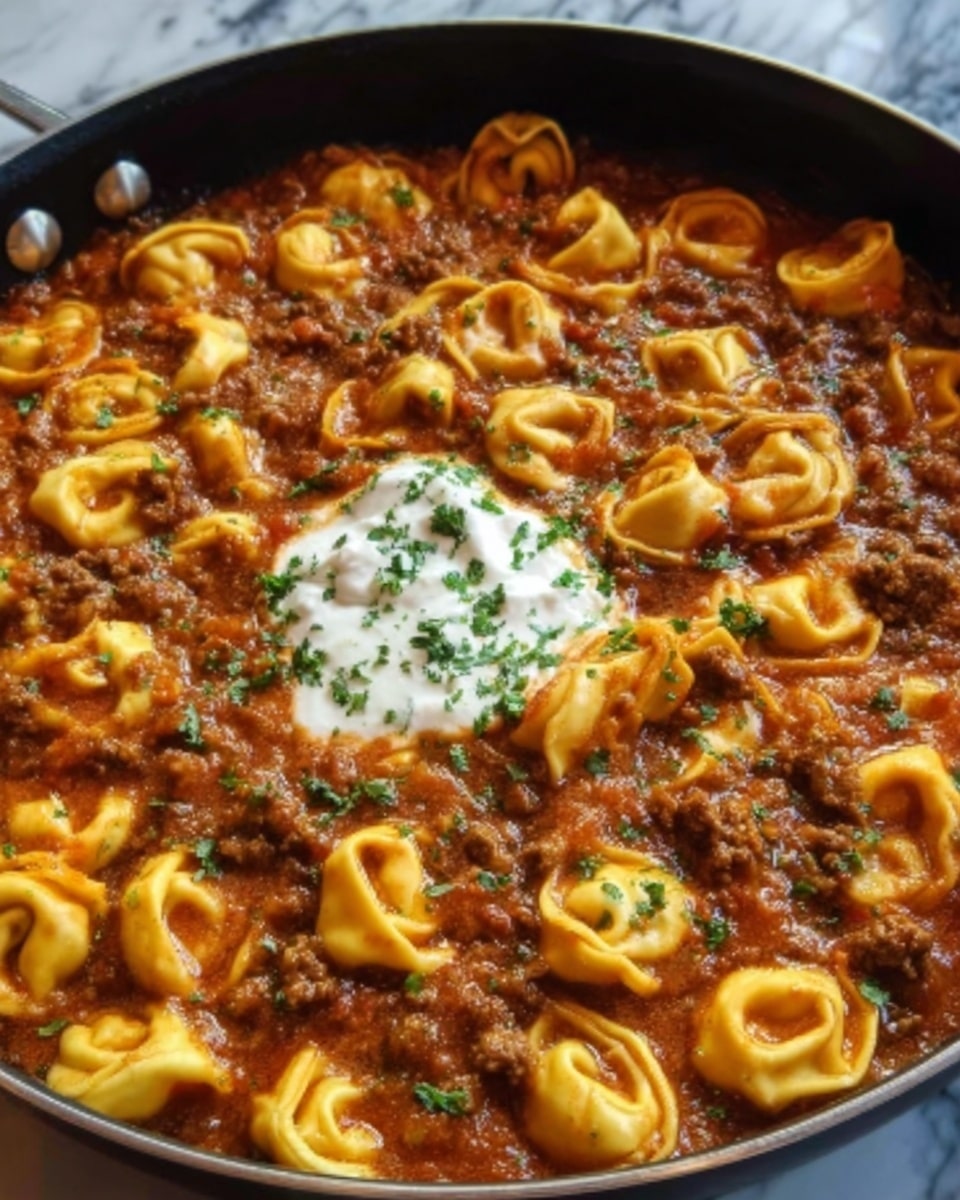 A close-up of a deep white bowl filled with tortellini pasta covered in thick, rich tomato sauce mixed with ground meat. The pasta is golden yellow and soft, while the sauce is dark red with visible chunks of meat and green herbs sprinkled on top. In the center, there is a dollop of white creamy sauce with a small green basil leaf on it. The bowl sits on a white marbled surface, and a woman's hand is reaching in from the right side holding a spoon. photo taken with an iphone --ar 4:5 --v 7