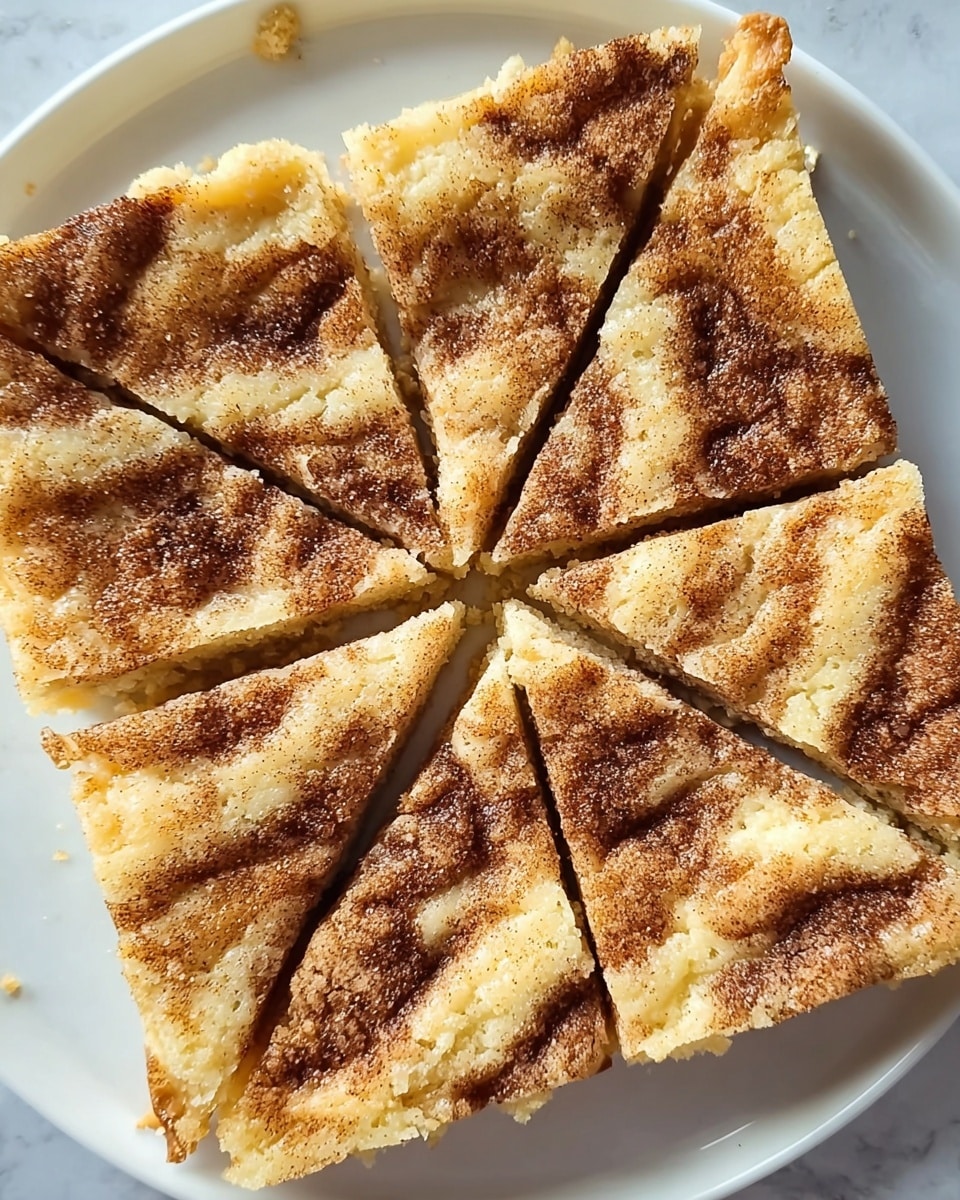 A square-shaped dessert cut into eight triangular slices is placed on a white plate on a white marbled surface. The top layer is light golden brown with a crumbly texture, patterned with darker swirls of cinnamon sugar that appear in curved lines and small clusters, especially concentrated in the center. The edges of the dessert are slightly rough, showing a thicker crust with some crumbs scattered around. The inner texture looks soft and slightly dense, contrasting with the sugary top. Photo taken with an iphone --ar 4:5 --v 7