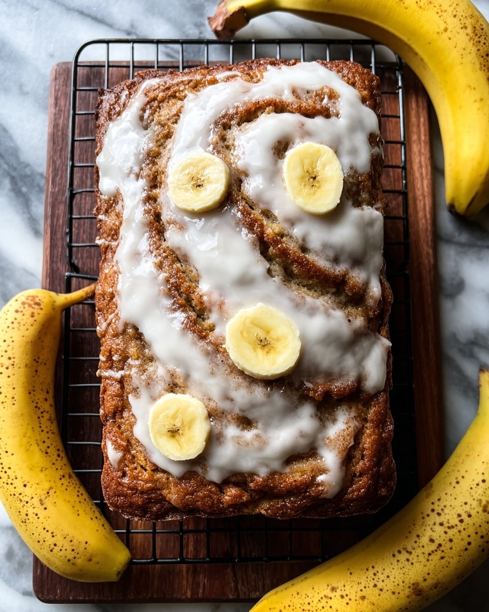 A square banana bread loaf with a golden-brown crust sits on a dark wooden cooling rack atop a white marbled surface. The top of the loaf is swirled with a thick layer of white icing, slightly melted and glossy, letting some of the brown cinnamon-spiced bread peek through in curved ridges. Embedded in the top layer are three round banana slices with visible seeds, adding a creamy yellow contrast to the bread and icing. Surrounding the loaf on the cooling rack are three whole ripe bananas with brown spots, adding a natural touch to the scene. Photo taken with an iphone --ar 4:5 --v 7