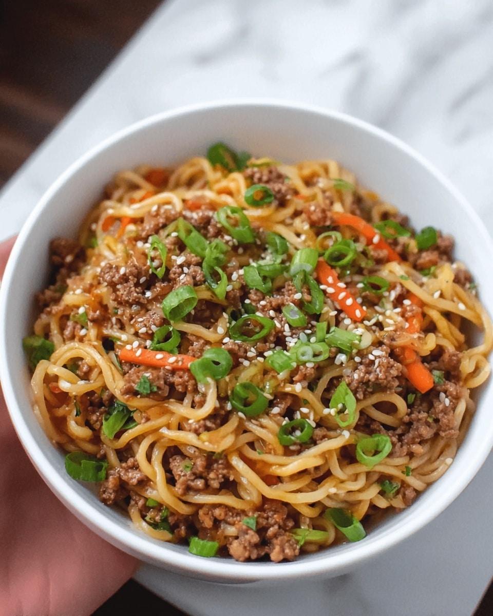A white bowl filled with cooked noodles mixed with small pieces of ground meat and thin carrot slices, topped with chopped green onions and sesame seeds. The noodles are light brown, glossy, and soft-looking, with the green onions adding a fresh green color scattered on the top. The bowl sits on a white marbled texture surface, and a woman's hand is holding the edge of the bowl. Photo taken with an iphone --ar 4:5 --v 7