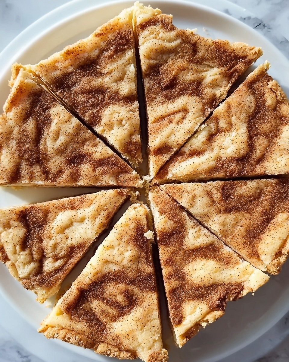 A square dessert cut into eight triangular slices is arranged on a white plate. The top layer is light golden brown with darker swirls and patches of cinnamon-colored powder, creating a marbled effect. The texture looks crumbly and soft with some small crumbs scattered on the surface and a slightly cracked appearance near the edges. The dessert is thin and evenly sliced with a rustic, homemade look. The plate sits on a white marbled surface. photo taken with an iphone --ar 4:5 --v 7